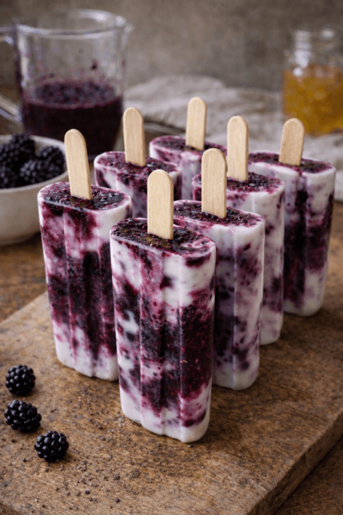 “Blackberry yogurt pops on a ceramic plate with fresh blackberries — simple, seasonal frozen yogurt recipe.”