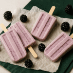 “Blackberry yogurt pops on a ceramic plate with fresh blackberries — simple, seasonal frozen yogurt recipe.”
