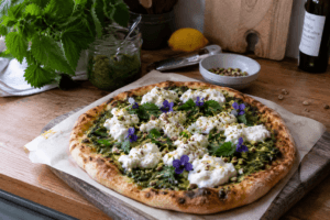 homemade nettle pesto pizza with burrata pistachios lemon zest and edible flowers