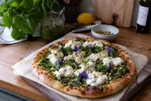 homemade nettle pesto pizza with burrata pistachios lemon zest and edible flowers